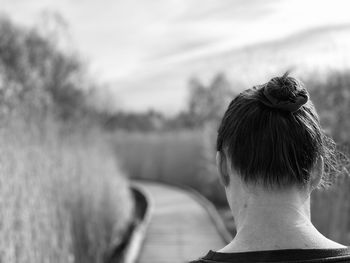 Black and white monochrome rear view of woman walking on a boardwalk