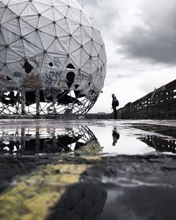 Man standing by abandoned dome on wet building terrace at teufelsberg during monsoon