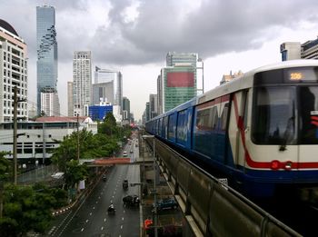 Cars on road in city against storm clouds