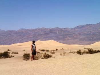 Full length of man standing in desert against clear sky on sunny day