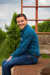 Portrait of smiling man sitting against sky