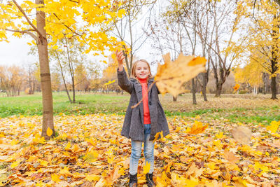 Full length of a girl standing on autumn leaves