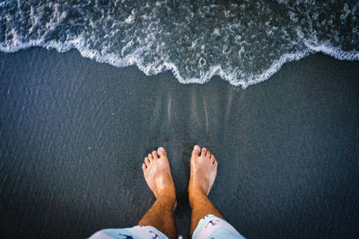 Low section of person standing on beach