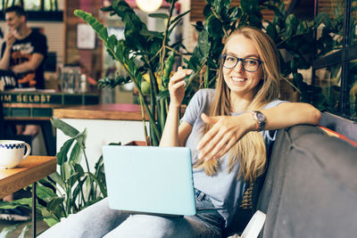 Young energetic successful positive woman with laptop on sofa in cafe.