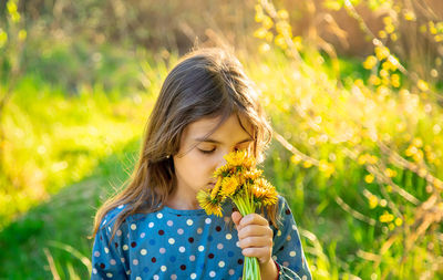 Girl with eyes closed smelling flower