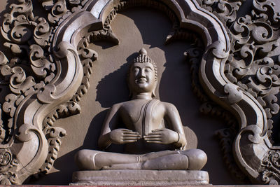 Low angle view of buddha statue against building