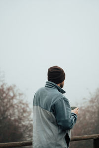 Rear view of man standing against clear sky