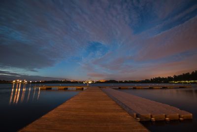 Pier over lake against sky at sunset