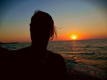 Silhouette woman on beach against sky during sunset