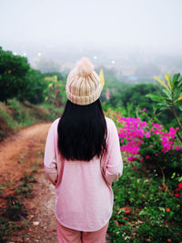 Rear view of woman standing on field against sky