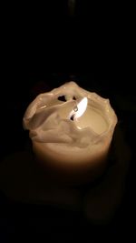 Close-up of illuminated candle in darkroom