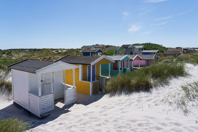 Houses on beach by buildings against sky