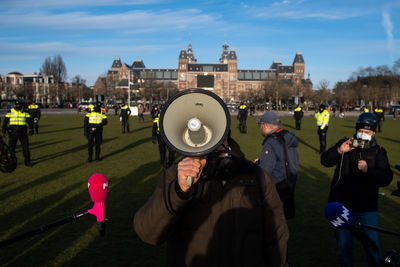 People photographing in city against sky