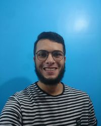 Portrait of smiling young man against blue sky