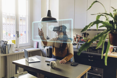 Woman wearing vr glasses touching transparent screen at home