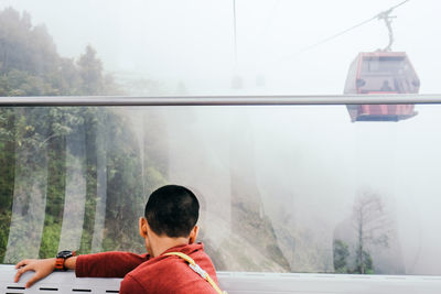 Man sitting by window watching cable car