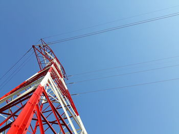 Low angle view of electricity pylon against clear blue sky