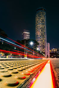 Illuminated light trails on building against sky at night