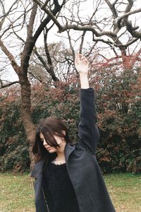 Woman with hand raised standing at park