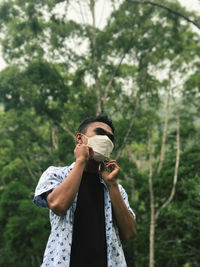 Man wearing protective face mask against trees