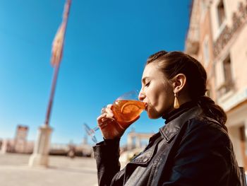 Portrait of young woman drinking wine in city