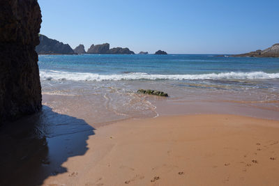 A quiet fine sandy beach with cliffs in the background