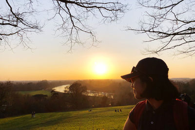 Man standing by tree against sky during sunset