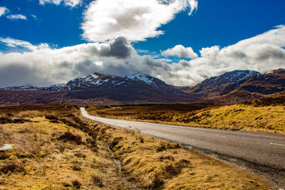 Road leading towards mountains against sky