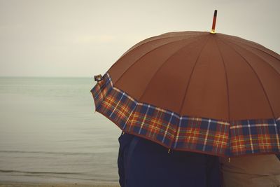 Rear view of man standing on beach against sky