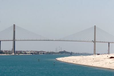 Suspension bridge over sea against sky