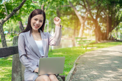 Young woman using phone while standing on plant