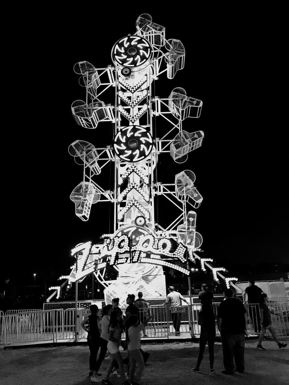 PEOPLE AT AMUSEMENT PARK RIDE AGAINST SKY AT NIGHT