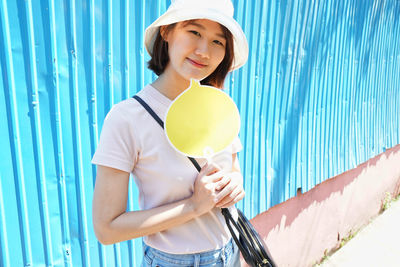 Portrait of woman holding speech bubble standing against wall