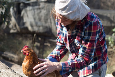 Mature woman with hen at farm