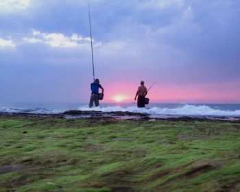 People enjoying on beach against cloudy sky