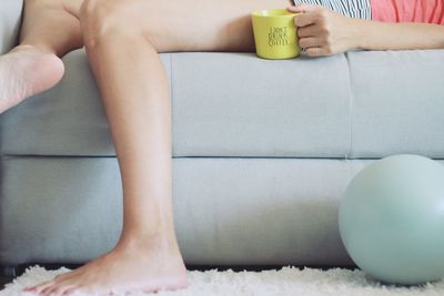 Low section of woman sitting on sofa at home