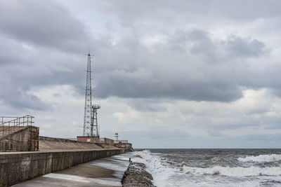 Electricity pylon by sea against sky