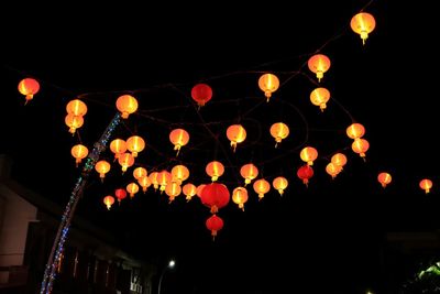 Low angle view of illuminated lanterns against sky at night