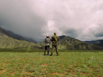 Rear view of men on field against sky