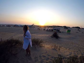 Rear view of woman walking on beach against clear sky