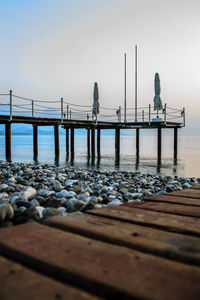 Seagulls perching on pier at sea against clear sky