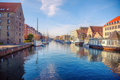 Buildings by river against sky