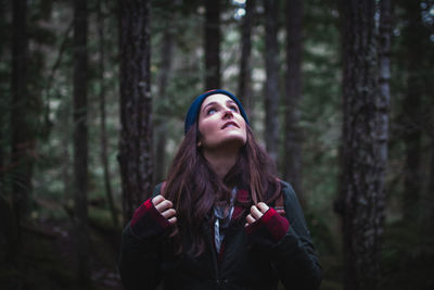 Close-up of young woman looking up in forest
