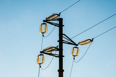 Low angle view of electricity pylon against clear blue sky