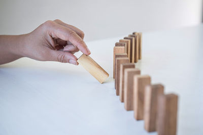 Cropped hand arranging wooden block over white background