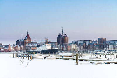 Boats on frozen river in city against sky