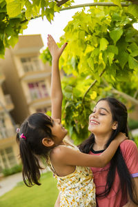 Side view of young woman standing against trees