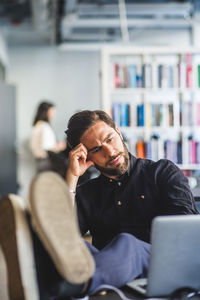 Tensed businessman looking at laptop while sitting in office