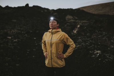 Woman wearing headlamp standing with eyes closed at caldera blanca volcano, lanzarote, canary islands, spain