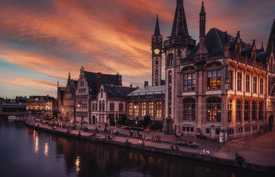 Illuminated buildings in city at sunset